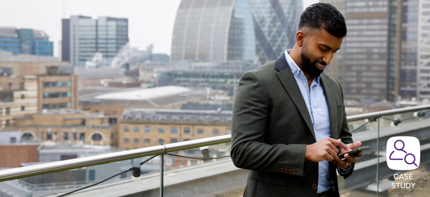 man on smartphone, standing on rooftop with city buildings in the background