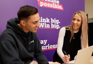 This image shows two people sat down talking together. 