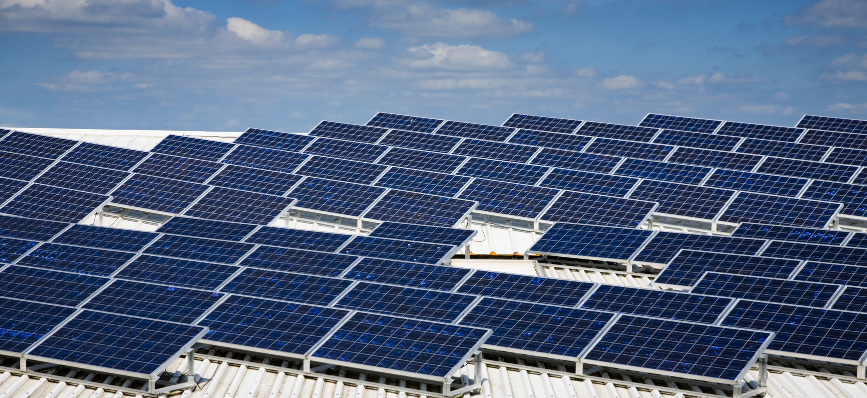 A worker using a laptop on a roof covered with solar panels A worker using a laptop on a roof covered with solar panels