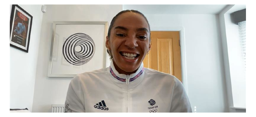 Team GB sprinter Ashleigh Nelson, wearing a white Team GB jacket and smiling into the camera