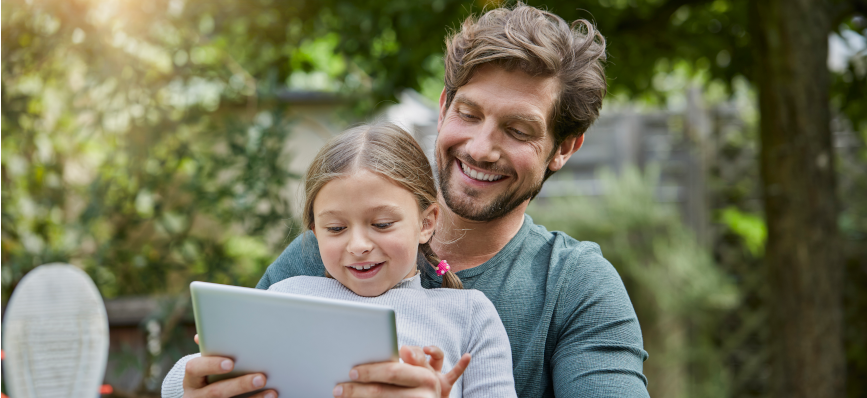 Father and daughter using tablet together in garden
