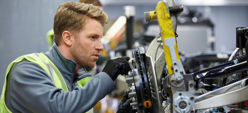 This image shows a male working on a piece of machinery in a warehouse. 