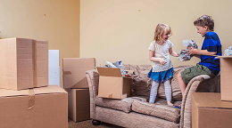Two children on sofa surrounded by boxes